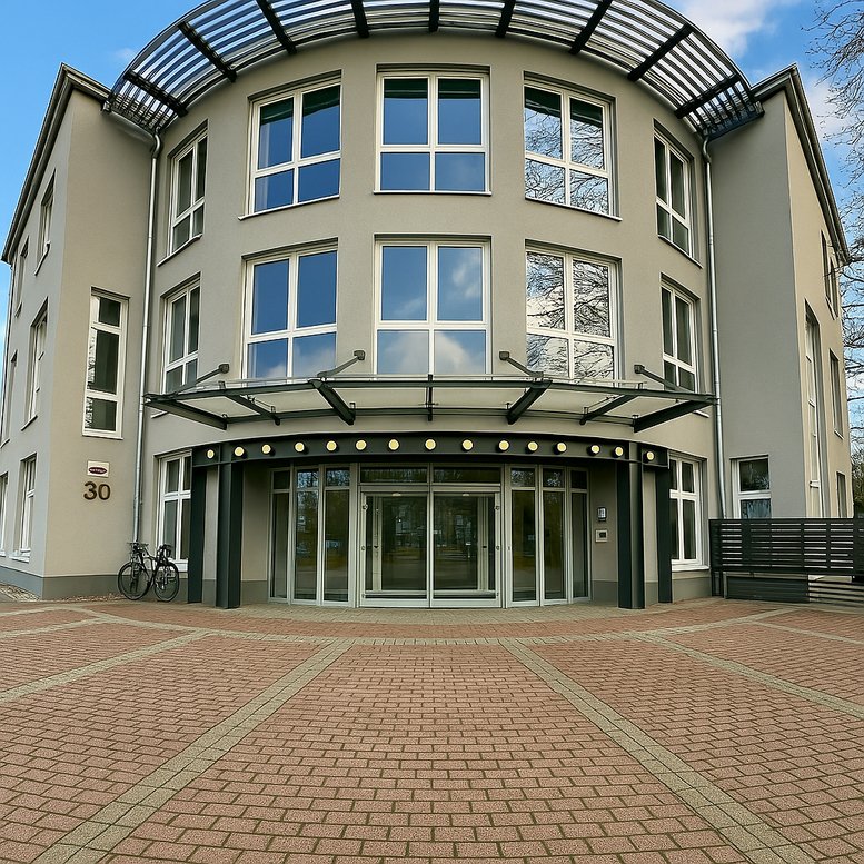 Curved exterior facade of the Alte Wittener Strasse 30 office building with a paved entryway.