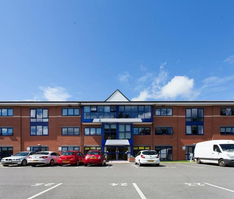 Exterior view of the brick facade and parking area at Atlas House, Caxton Close, Wigan.