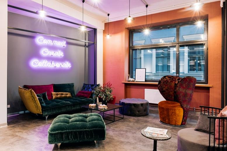 Lounge at Audeju 15 with colorful velvet sofas and neon wall art.