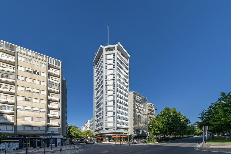 Exterior view of the white high-rise building at Avenida da República nº 18 under a clear blue sky.