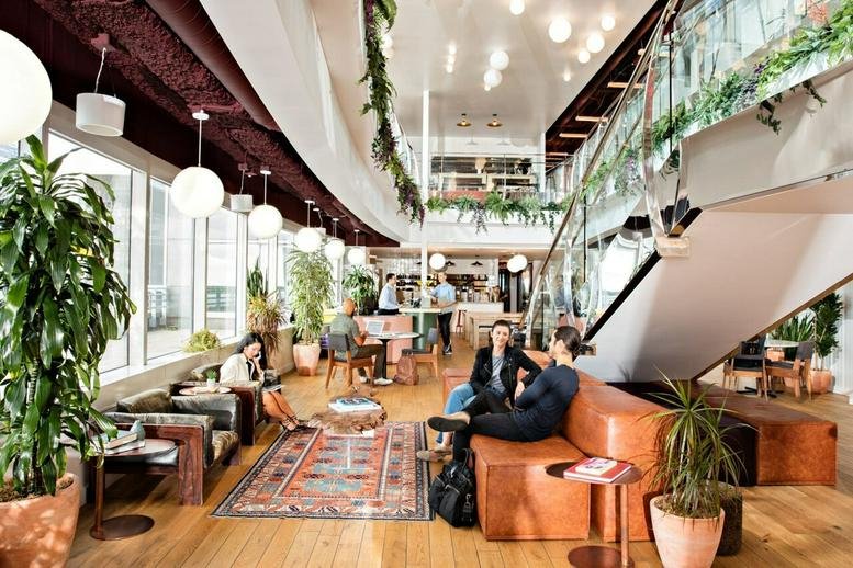 Spacious communal lounge at Aviation House, 125 Kingsway, featuring warm leather seating and hanging plants.