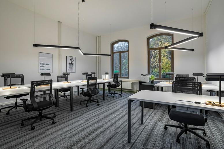 Bright open-plan office at Bödekerstraße 1 with rows of white desks and ergonomic black chairs.