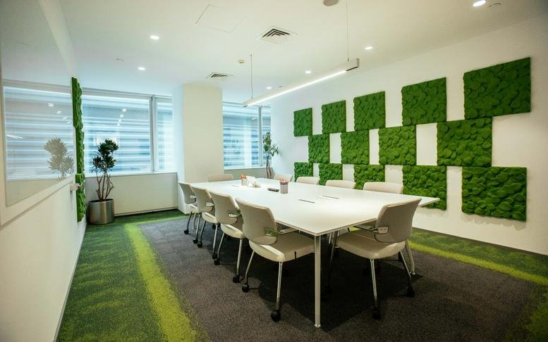 Meeting room at Büyükdere Cd. No: 173, Istanbul featuring a white conference table and green moss wall art.