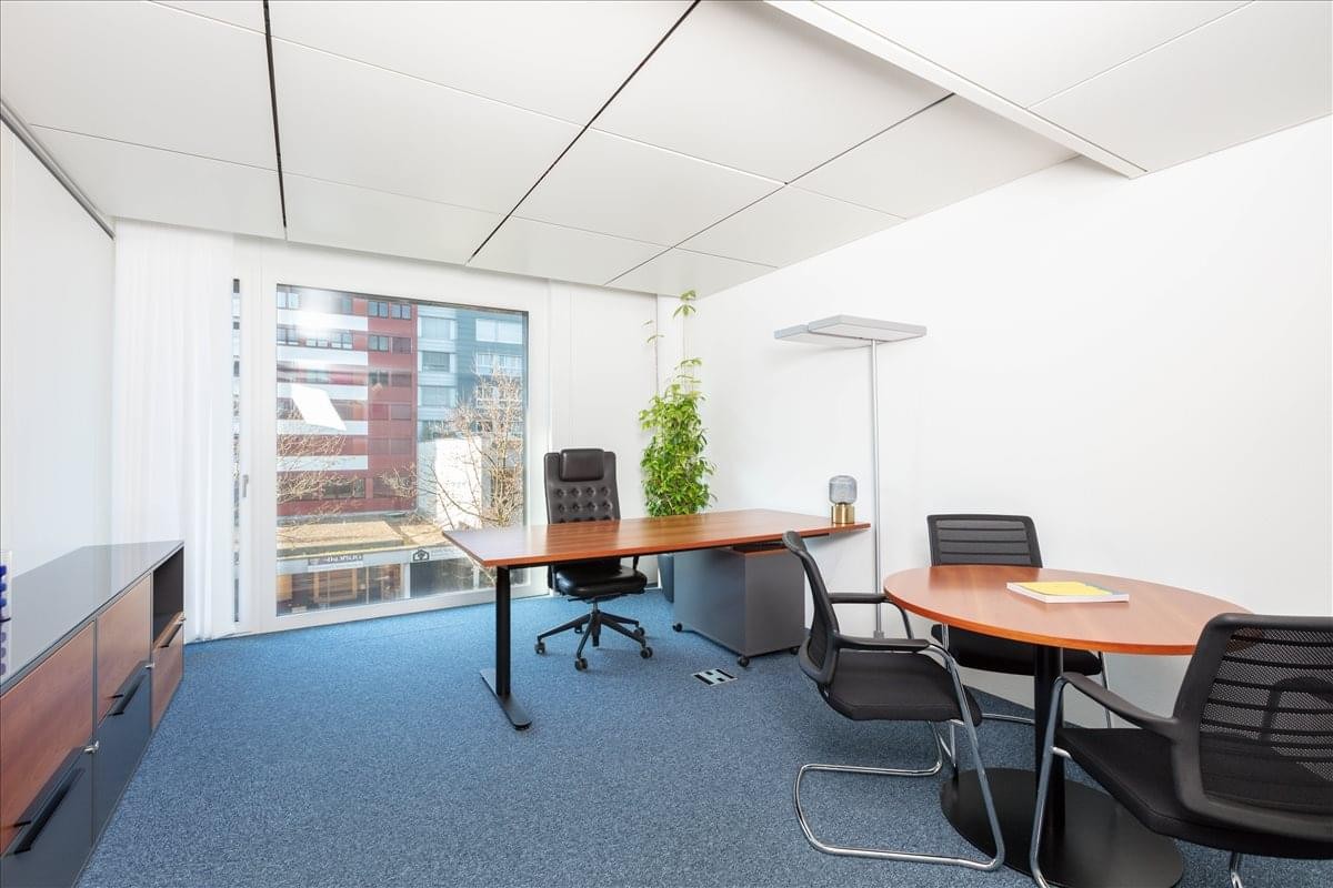 Spacious private office at Baarerstrasse 52 with large windows and a separate meeting table.