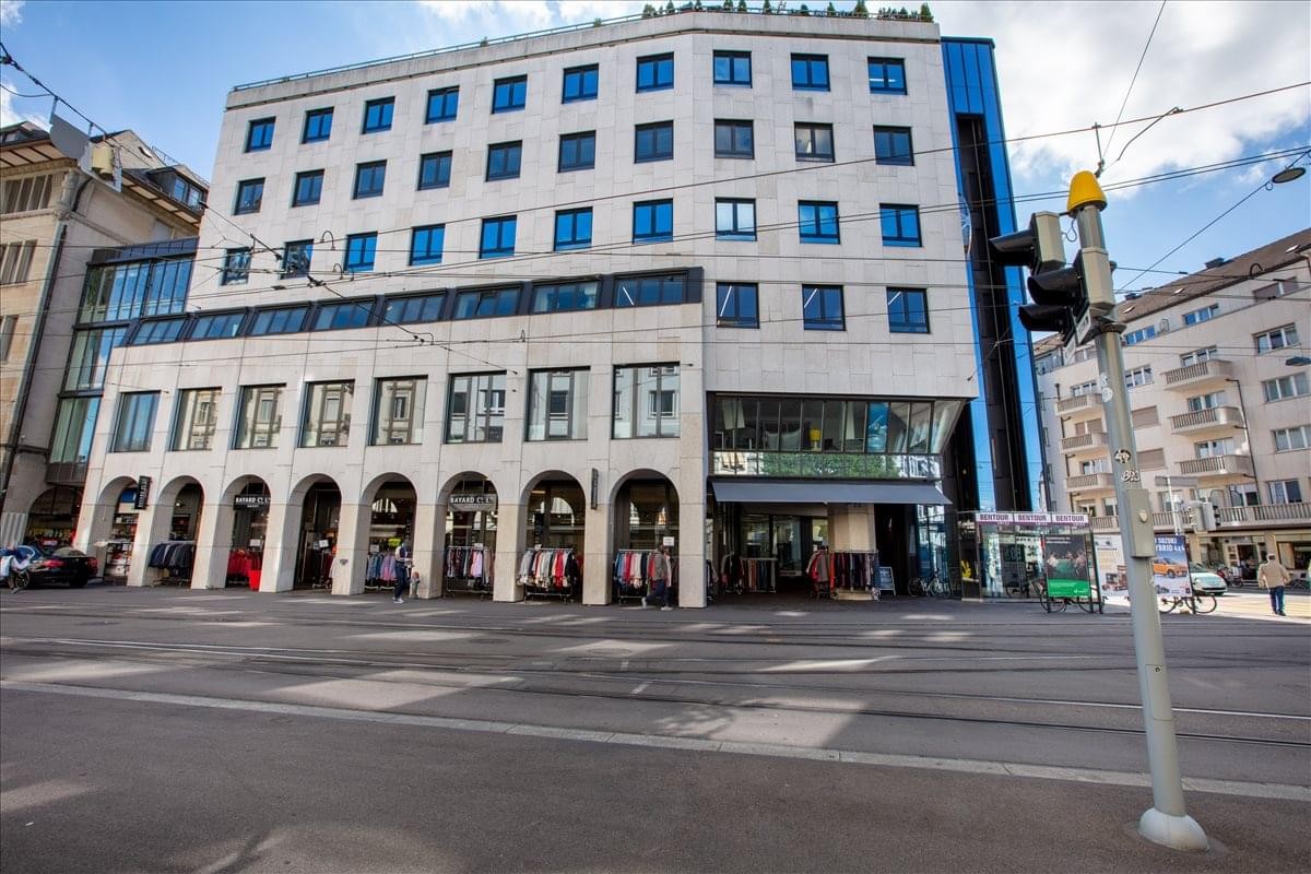 Exterior view of the white stone building facade at Badenerstrasse 47, Zurich.