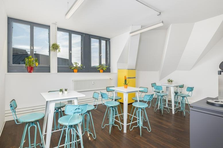 Spacious communal dining area at Bahnhofplatz 8, Winterthur with blue bar stools and a yellow fridge.