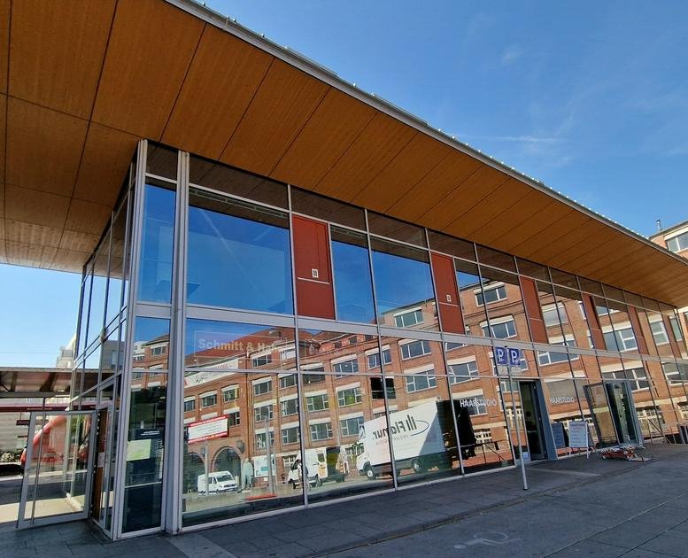 Modern glass-facade exterior of the Bahnhofsplatz 2, Rüsselsheim am Main, Rhein-Main building under a blue sky.