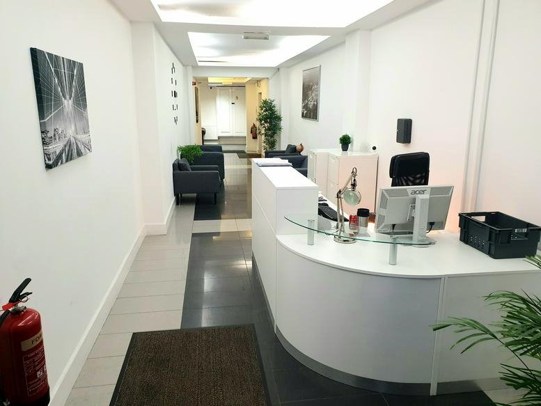 Bright reception area of Balfour Business Centre with a curved white desk and modern lighting.