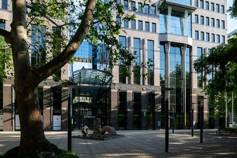 Exterior facade of the Bank Center, Szabadság tér 7 building through lush green trees.