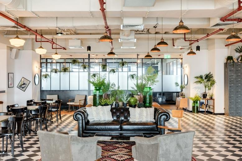 Spacious communal lounge at Globalworth Campus A with leather sofas and checkerboard floors.