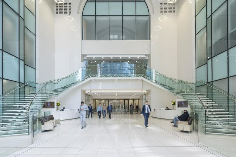 Grand white lobby with symmetrical glass staircases and high ceilings.