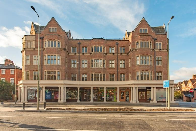 Red brick exterior of Belsyre Court, Woodstock Road, Oxford with classic architecture and ground floor shops.