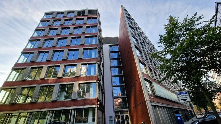 Modern exterior of the Atlantic Haus building featuring a brick and glass facade with a sharp architectural angle.