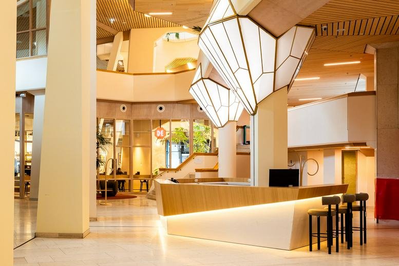 Bright reception area of Bijlmerplein 888 featuring a modern desk and geometric pendant lighting.