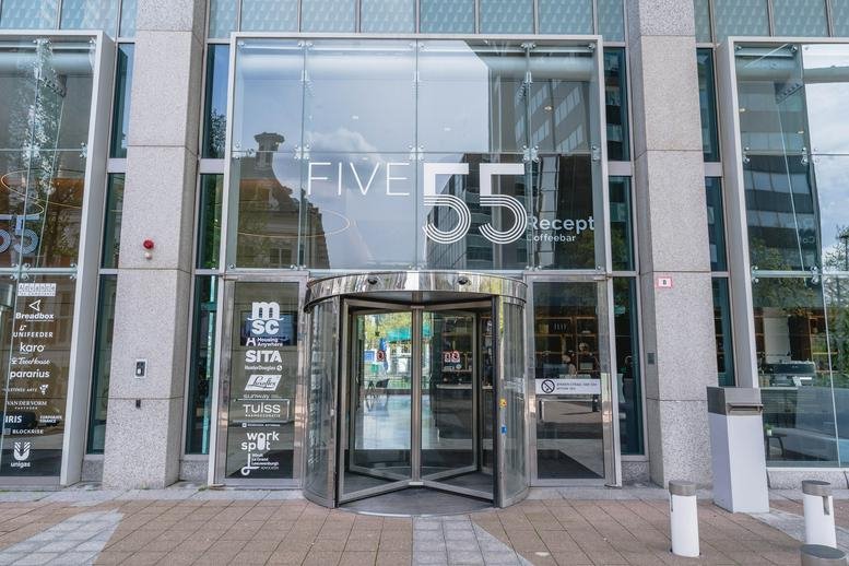 Exterior entrance of the Blaak 555 building with a revolving glass door.