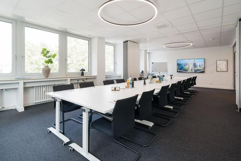 Bright conference room featuring a large table, circular pendant lights, and city views.