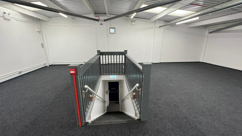 Spacious open-plan mezzanine at Concord House with grey carpeting and white walls under a pitched roof.