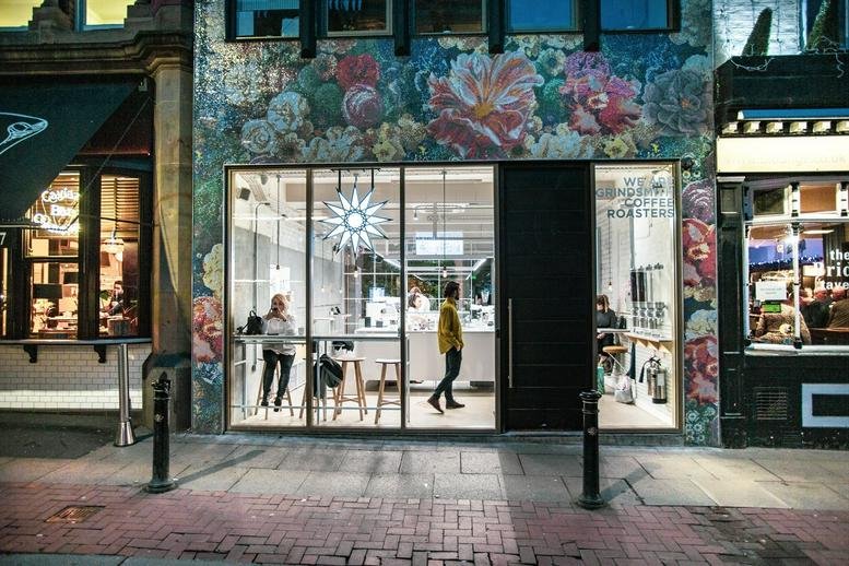 Street-level entrance with large glass windows and a vibrant floral mural above.