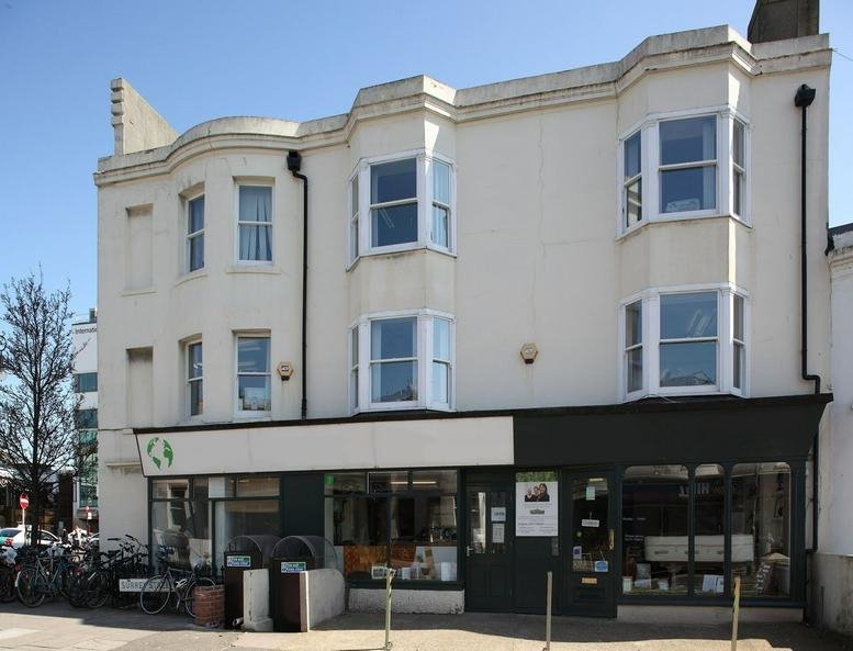 Exterior facade of the white Brighton Eco-Centre building with large bay windows and street-level storefronts.