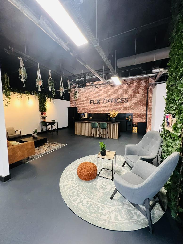 Spacious communal lounge at Brouwersgracht 3, Veenendaal, Utrecht with grey armchairs and a brick feature wall.