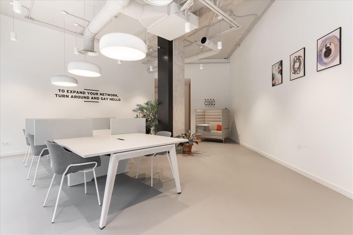 Spacious coworking area at C/ Méndez Ávaro 20 with white desks and hanging globe lights.