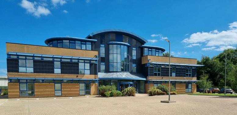 Exterior view of the contemporary facade at Caerphilly Business Park under a blue sky.