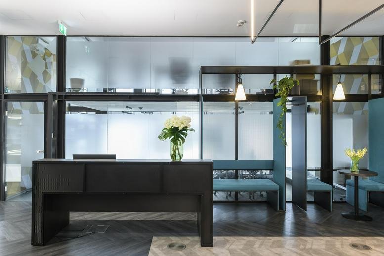 Reception desk at Calea Griviței 82-98 with dark wood finish, white flowers, and blue seating booths.