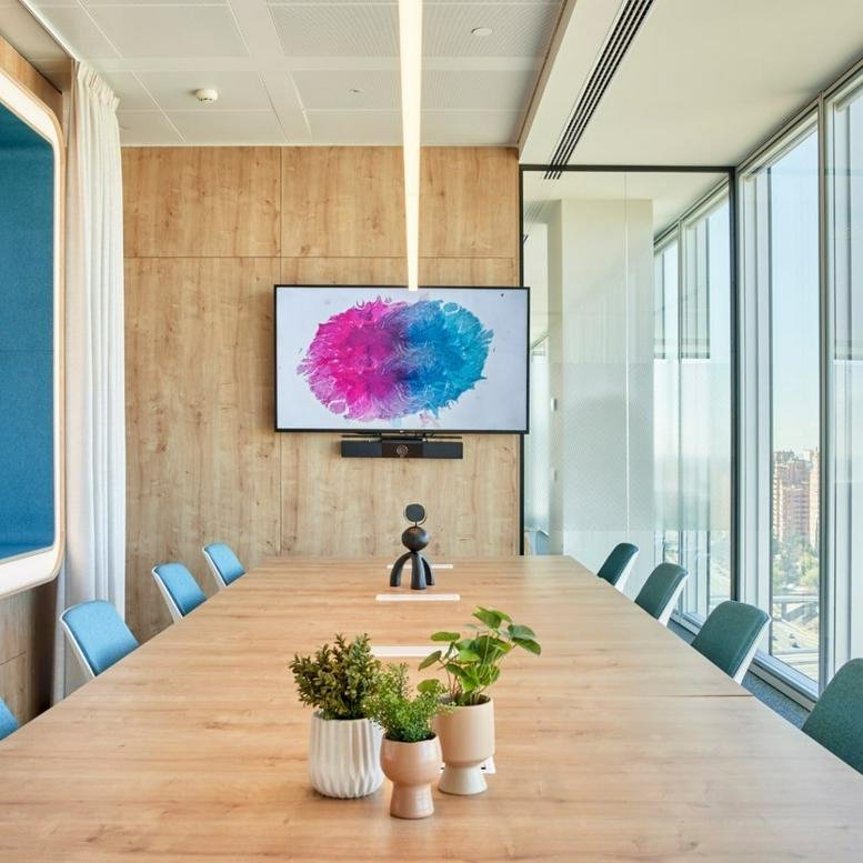 Spacious boardroom with a large wooden table and colorful art on the screen in Torre Chamartín.