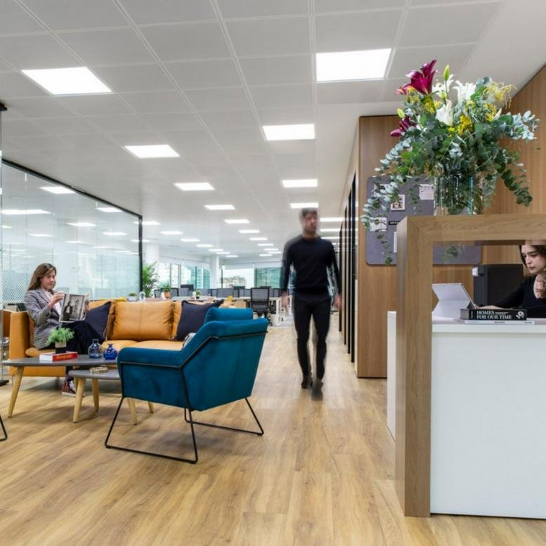 Spacious communal lounge and reception area at Calle del Eucalipto, 33 with a teal armchair and wood floors.