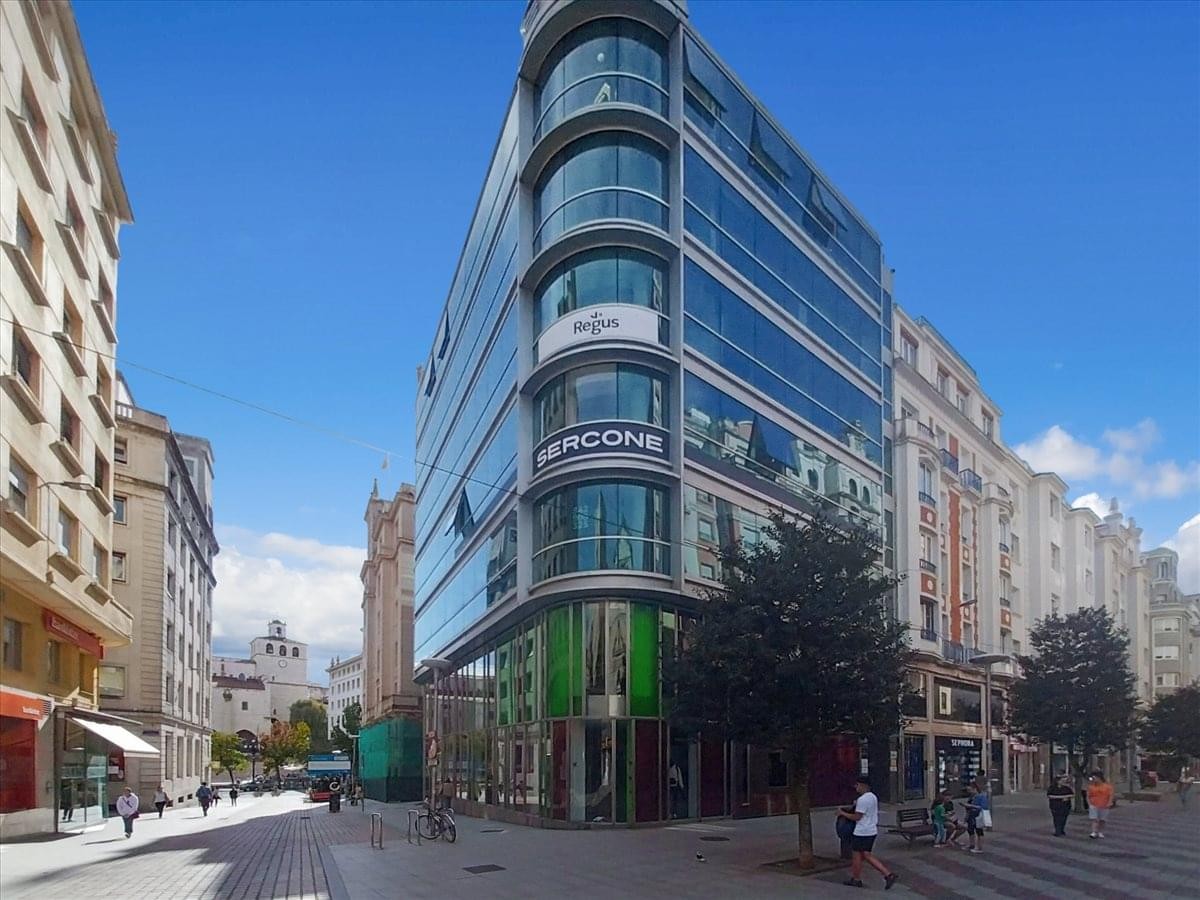 Exterior view of the curved glass-facade building at Calle Juan de Herrera, 18.