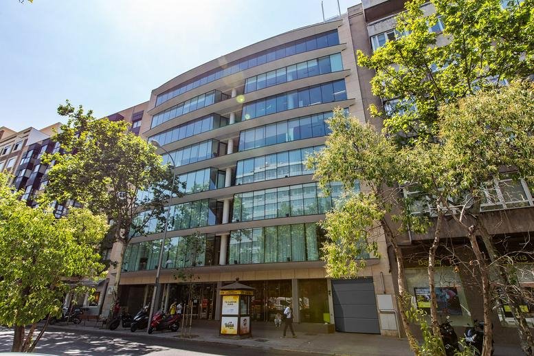 Exterior view of the multi-story glass facade building at Calle Maria de Molina 54.