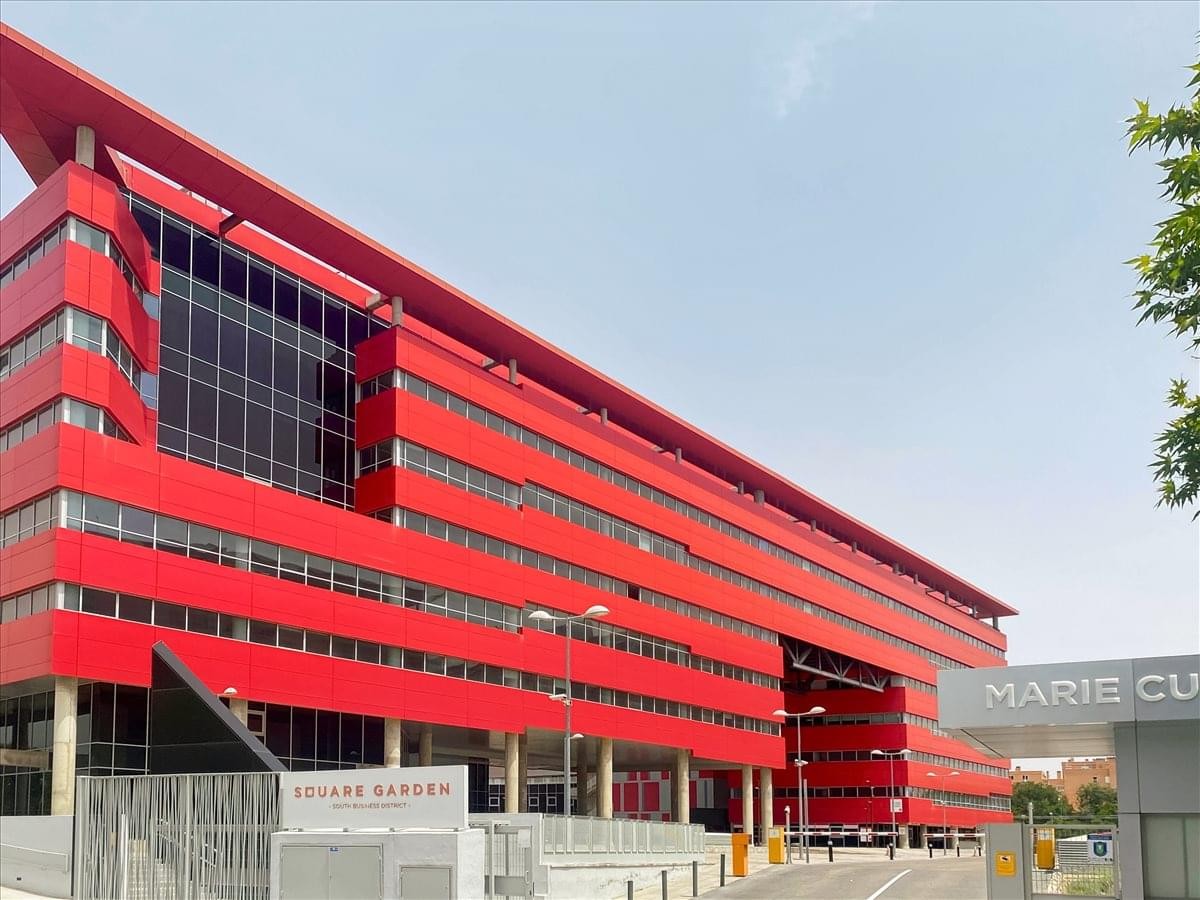 Exterior view of the vibrant red Rivas Square Garden building with large glass windows.