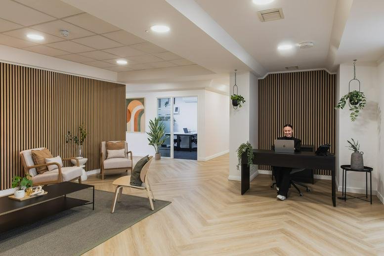 Reception and lobby area of Capital House, 25 Chapel Street with wood-slat walls and a person at the desk.