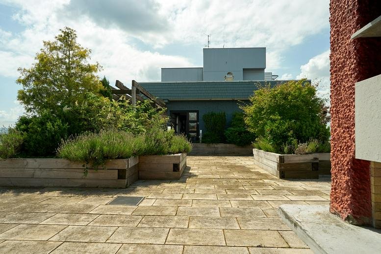 Rooftop terrace at Carl-Zeiss-Straße 5 with wooden planters and paved walkway.