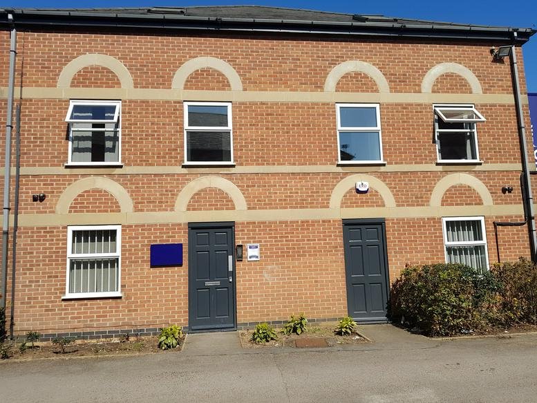 Brick exterior of Carlton Business Hub with arched window details and dark grey entrance doors.