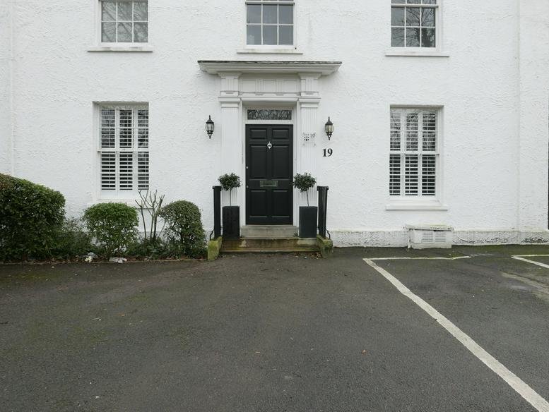 White Georgian facade and black entrance door of Carlton House, 19 West Street, Epsom.