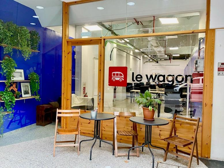 Entrance to Le Wagon at Carrer del Bruc, 149, with a branded glass facade and outdoor café seating.