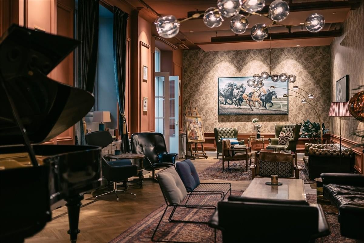 Spacious communal lounge at Centralplan 15, Våning 1, Stockholm with a grand piano and equestrian artwork.