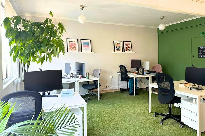 Spacious open-plan workspace at Char. Trikoupi 18, Athens featuring green flooring and vibrant wall art.