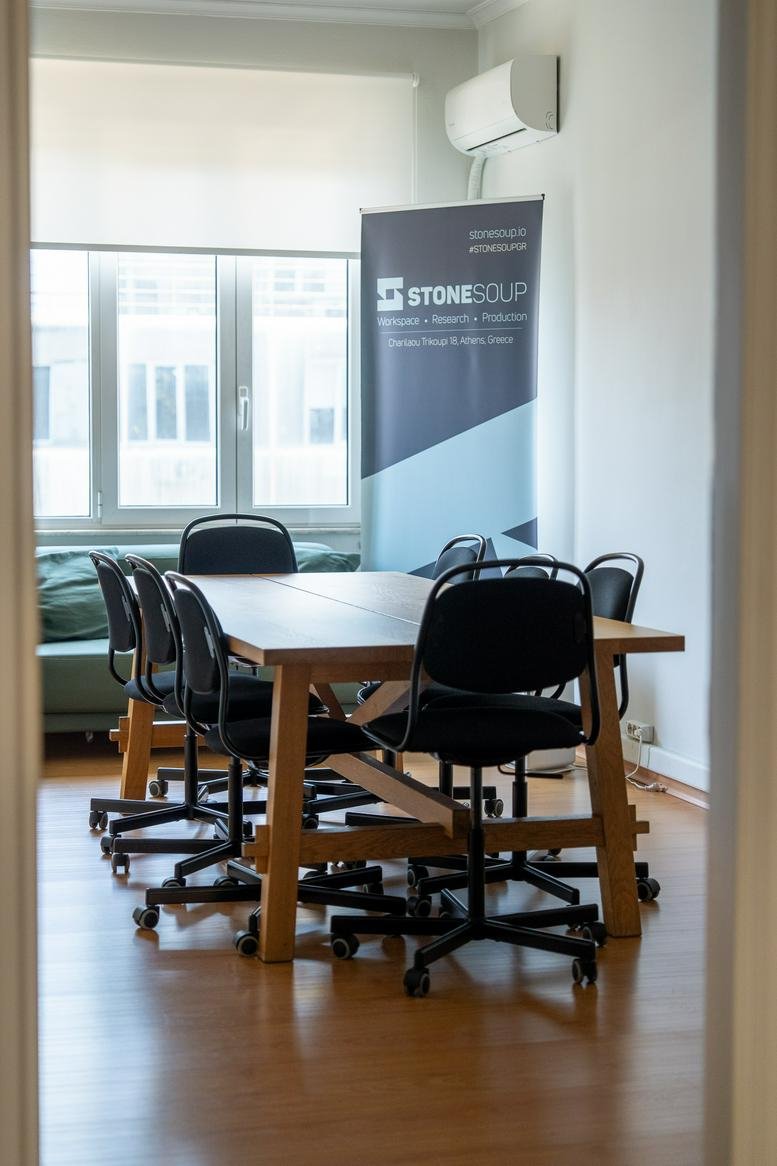 Spacious meeting room at Char. Trikoupi 18 featuring a wooden table and a branded banner.