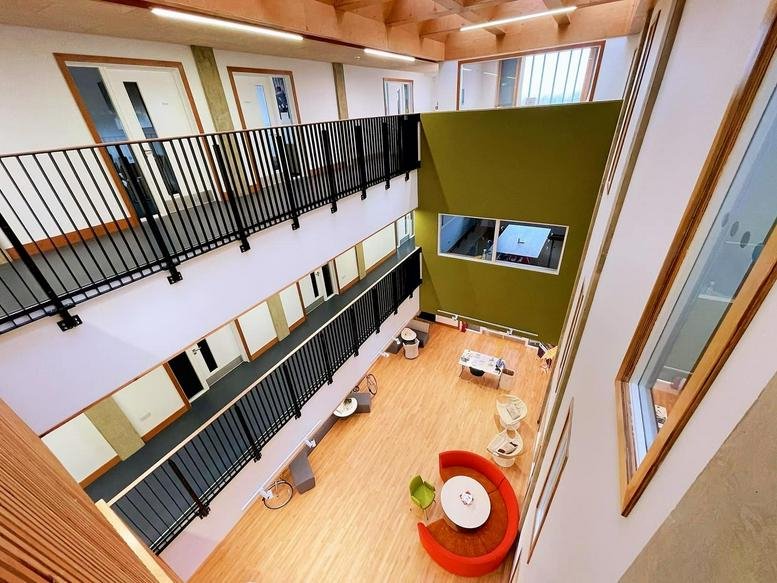 Multi-level atrium with wooden floors and colorful breakout furniture.