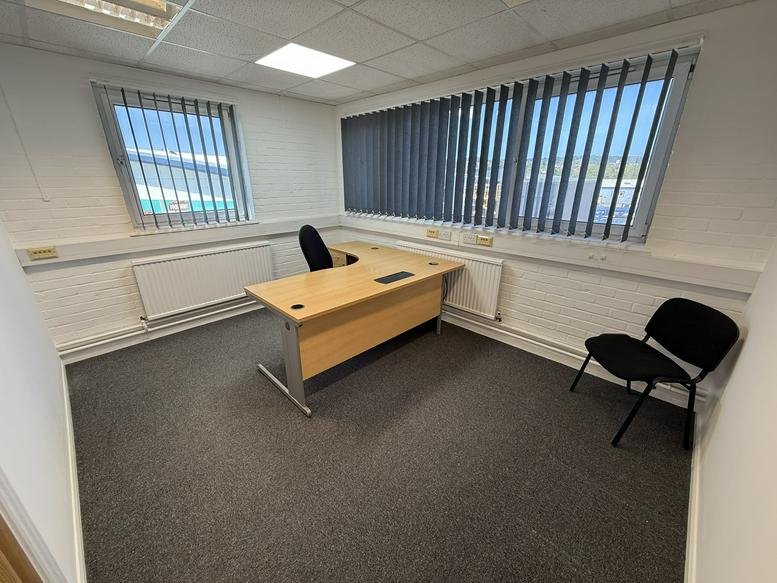 Office room with desk, chair, and large windows with blinds.