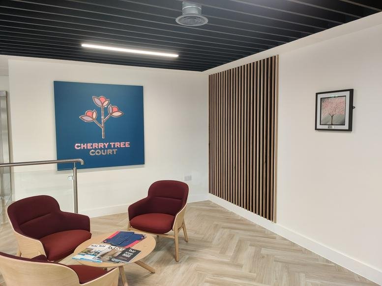 Bright reception area at Cherry Tree Court, 36 Ferensway featuring red armchairs and branded wall art.