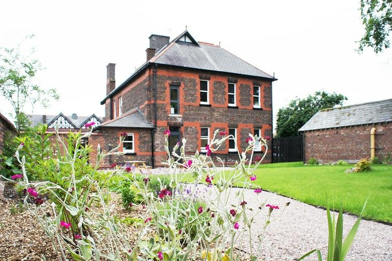 Exterior view of the historic brick Chimney Building, Clock Tower Park set against a green lawn.