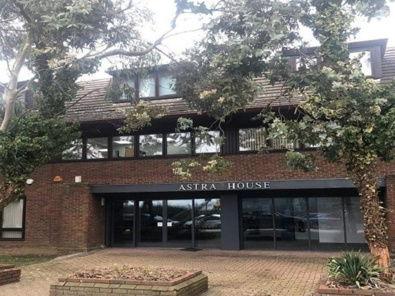 Exterior view of the brick-built Astra House office building with large windows and surrounding trees.