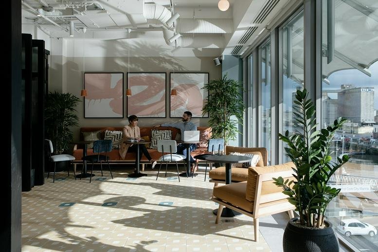 Spacious coworking lounge with floor-to-ceiling windows and abundant natural light.