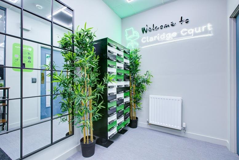 Bright reception area at Claridge Court with green plants and branded signage.