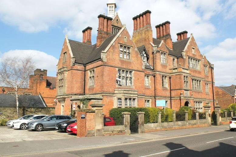 Grand red brick facade of the College Business Centre, Uttoxeter New Road, Derby featuring multiple ornate chimneys.