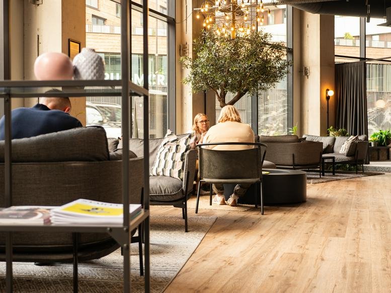 Spacious lounge area at Colony Coworking Piccadilly with velvet armchairs and large windows.