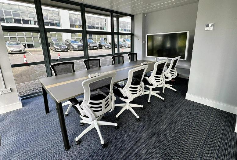 Spacious meeting room at Corporate Park 2, Suite 213, Dublin 15 featuring a long grey table and white chairs.